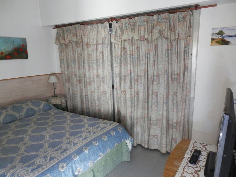 Dormitorio con cama matrimonial, TV y ventanal al balc&oacute;n